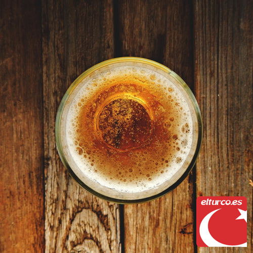 Vaso de cerveza rubia con espuma visto desde arriba sobre una mesa de madera rústica