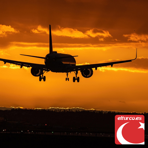 Avión de pasajeros en silueta aterrizando al atardecer bajo un cielo naranja