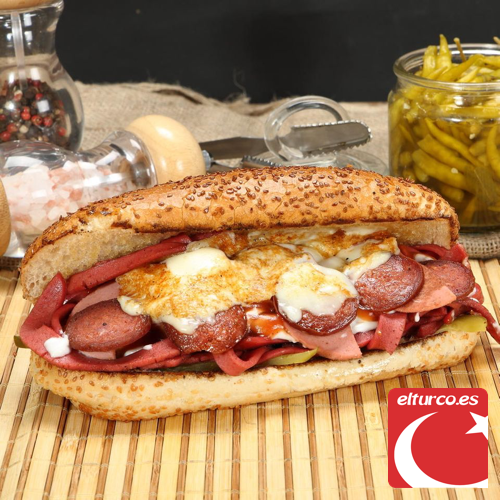 Sándwich tostado a la plancha, cortado en dos, en un plato de cartón sobre una mesa de madera azul