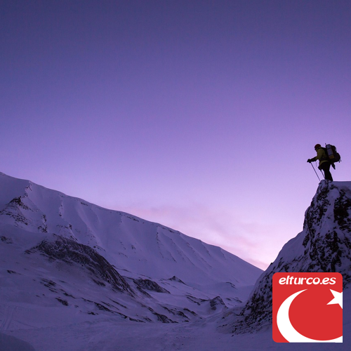 Cumbres nevadas de una montaña al atardecer, con nubes bajas entre las laderas